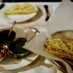 a plate of flatbreads, a bowl of salsa, and a bowl of olives