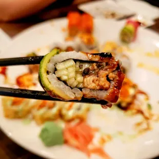 a closeup of a piece of sushi being held with chopsticks