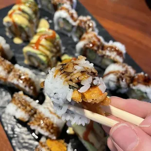 a hand holding a chopstick with a piece of sushi on it