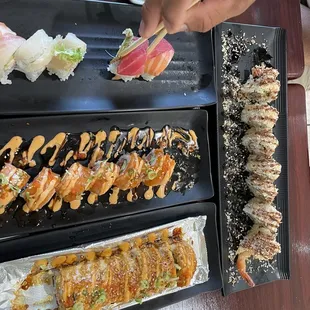 a person holding chopsticks over a plate of sushi