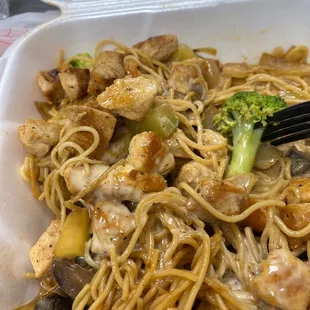 a close up of a bowl of noodles with chicken and broccoli