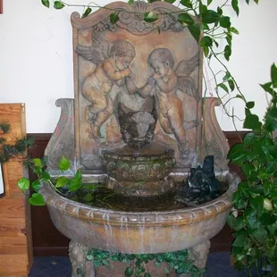 a water fountain with statues and plants