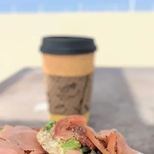 Bagel with lox and coffee enjoying it by the beach