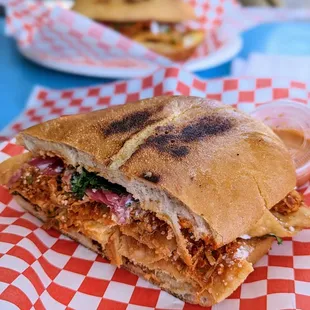 a sandwich on a red and white checkered paper