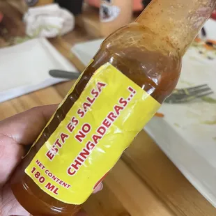 a hand holding a bottle of chili sauce
