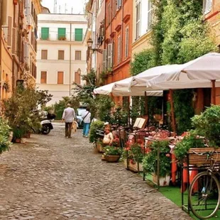 a cobblestone street with tables and umbrellas