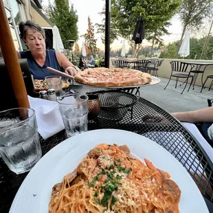 a woman sitting at a table with a plate of pasta