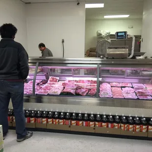 a man standing in front of a meat display