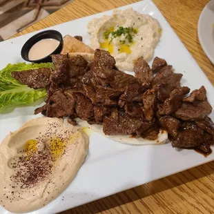a plate of meat and hummus