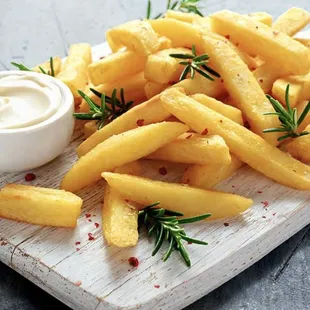 french fries on a cutting board with a dip