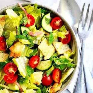 a bowl of salad with croutons and tomatoes