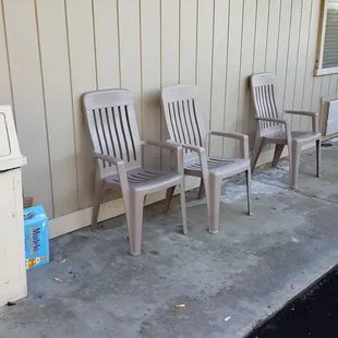 Our room is the first window past the chairs. Cigarette butts are all around, and the empty beer box is next to the trash.