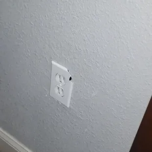 Exposed broken plug near entry door of room.