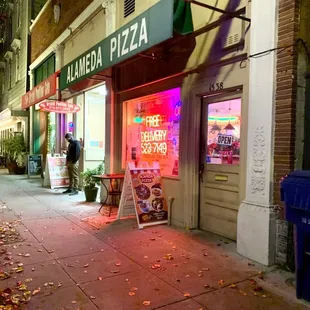 a neon sign in front of a pizza parlor