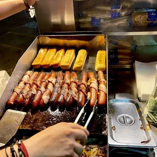 a person cooking hot dogs