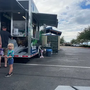 a little girl standing in front of a food truck