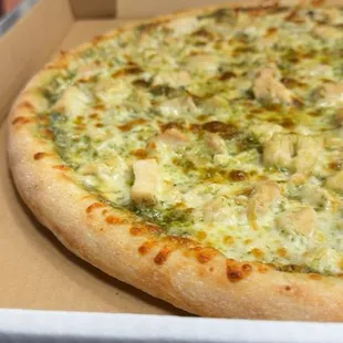 A pizza made with pesto sauce and chicken.
