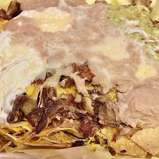 Carne Asada Nachos. Crisp but tender carne asada chunks with refried beans, cheese, guacamole, and sour cream.