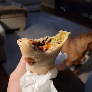 a person holding a burrito in their hand