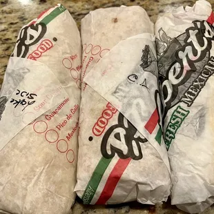 three burritos wrapped in paper