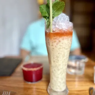 a tall glass with a straw and a mint leaf garnish