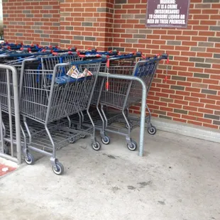 a row of shopping carts in front of a brick wall