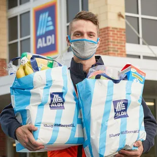 a man in a face mask holding two bags of groceries