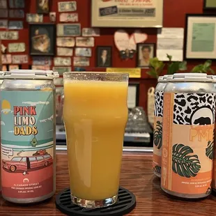 three cans of ale and a glass of orange juice