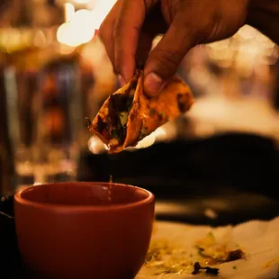 a hand dipping a piece of pizza