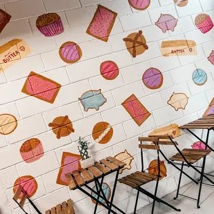 a table and chairs in front of a painted wall