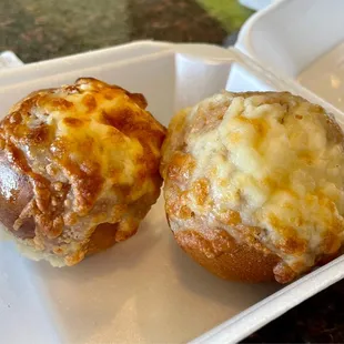 two baked potatoes in a styrofoam container