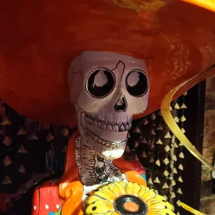 a skeleton in a sombren holding a sunflower