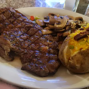 Ribeye steak with sautéed mushrooms and baked potatoe.