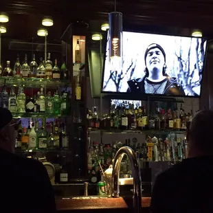 a man on a tv screen in a bar