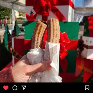 a person holding a pair of churros