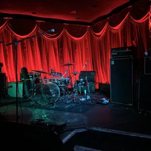 a stage with red curtains and a drum set