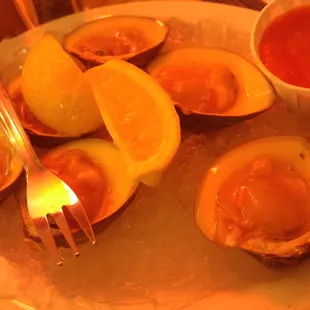 a plate of oysters with sauce and lemon wedges