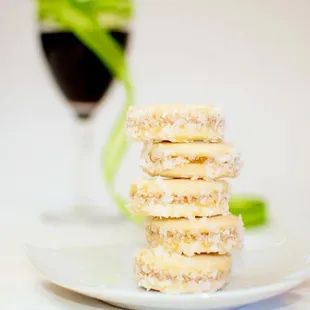 a stack of donuts on a plate with a glass of wine in the background