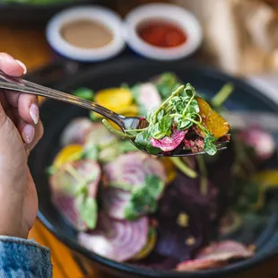 a person holding a fork with a salad on it
