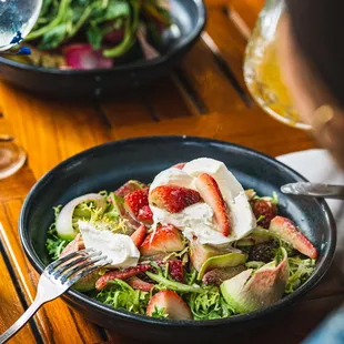 a woman eating a salad with strawberries