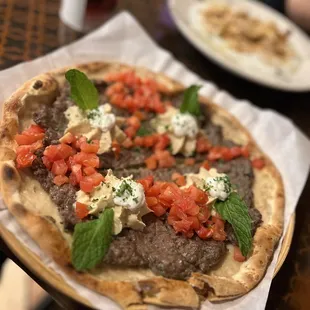 a steak pizza with tomatoes and cheese