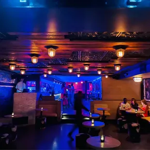 people sitting at tables in a dimly lit bar