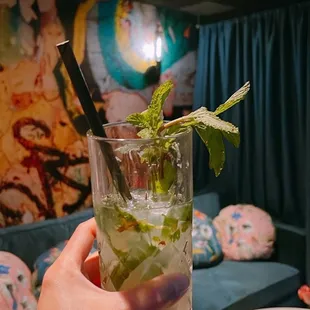 a person holding a glass of mojit