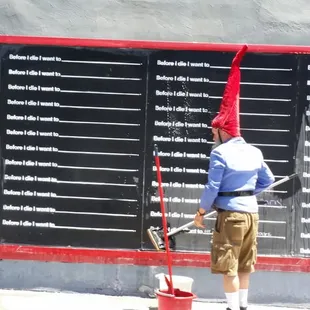 Outside wall &quot;Before I die, I want to ____&quot; chalkboard being cleaned by your friendly Gnome.