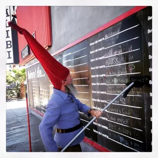 a man in a gnome hat writing on a blackboard