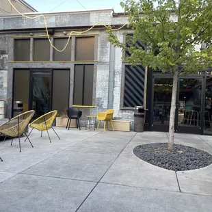 a patio with yellow chairs and a tree