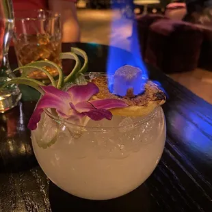 a cocktail with a purple flower garnish