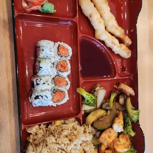 Bento box of hibachi shrimp, spicy tuna roll, shrimp tempura and fried rice.