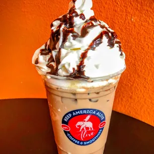 a cup of iced coffee with whipped cream and chocolate drizzle