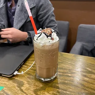 a person sitting at a table with a laptop and a drink